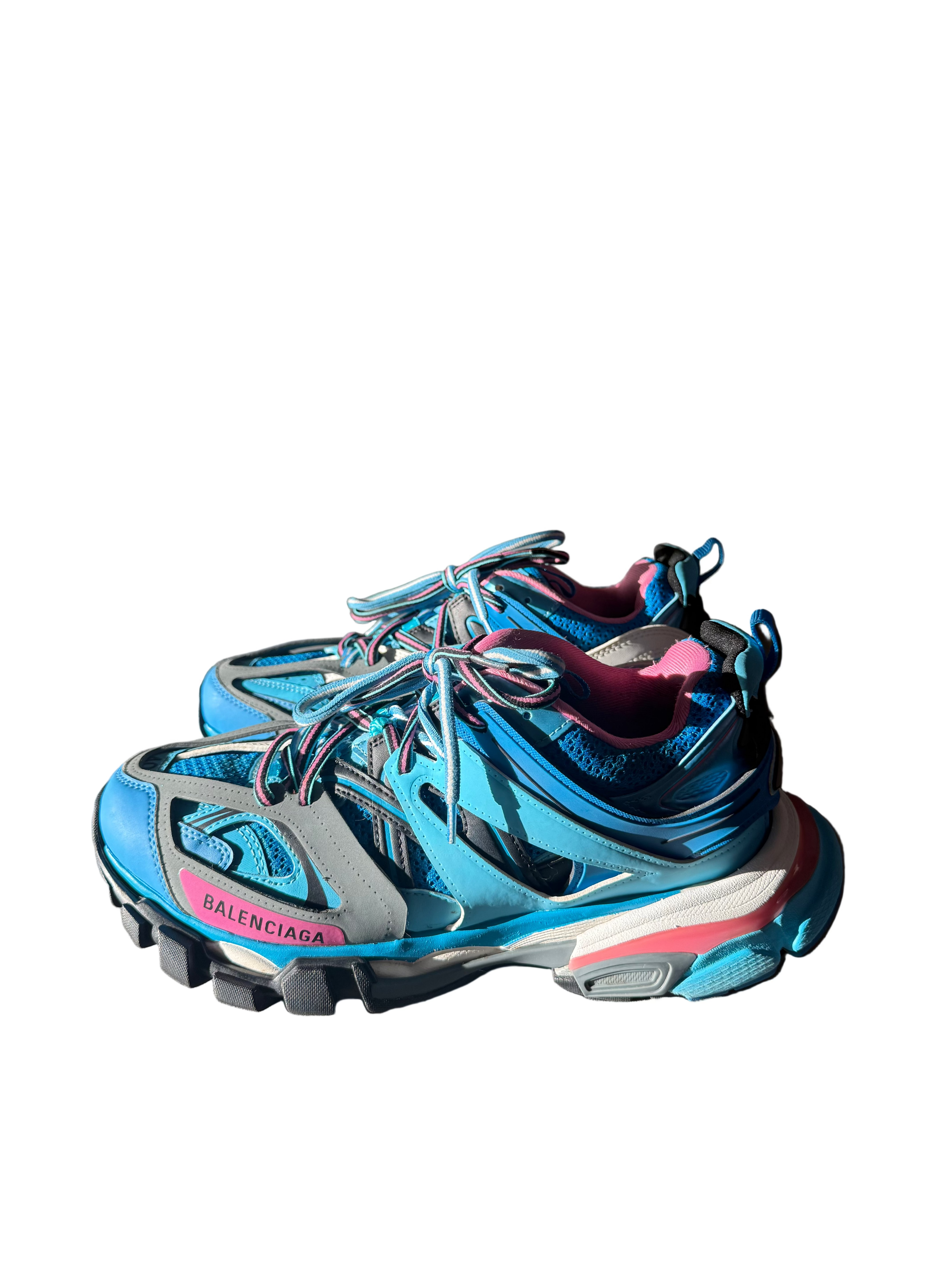 Blue Balenciaga sneakers with pink accents on a light gray surface, with a Balenciaga box in the background.